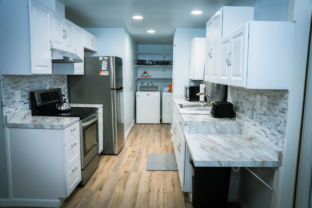 A modern kitchen with white cabinetry and a connected laundry area.