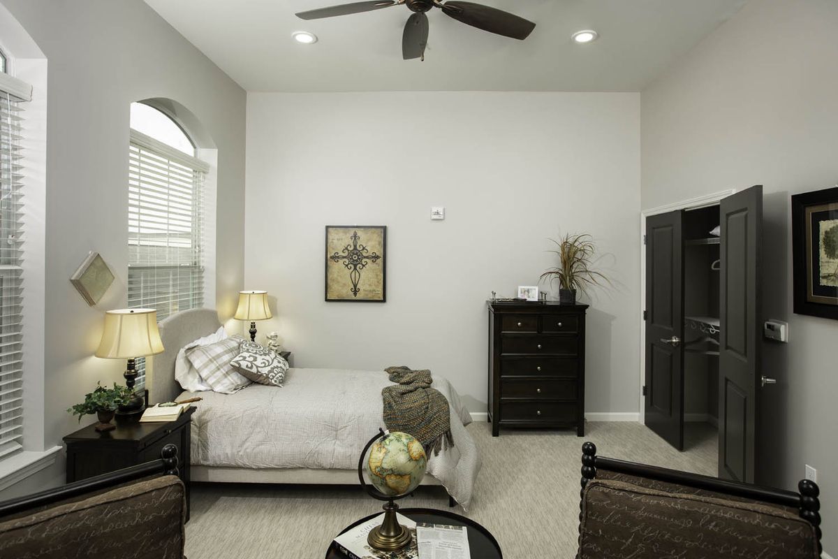A cozy bedroom featuring a neatly made bed, a tall dresser, and modern decor with a ceiling fan overhead.