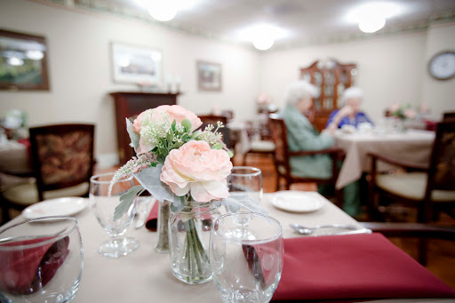 A cozy dining area for elderly residents, adorned with fresh flowers and set for a meal.