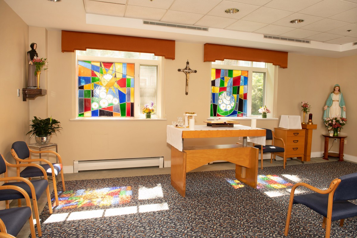 A small chapel featuring stained glass windows and an altar.