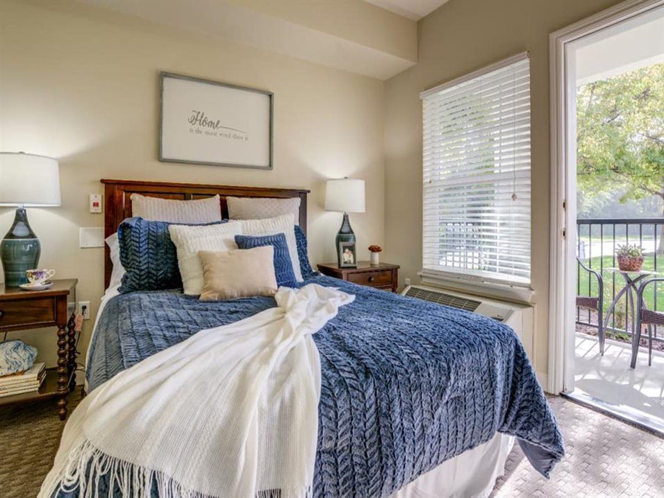 A cozy bedroom with blue bedding and ample natural light.