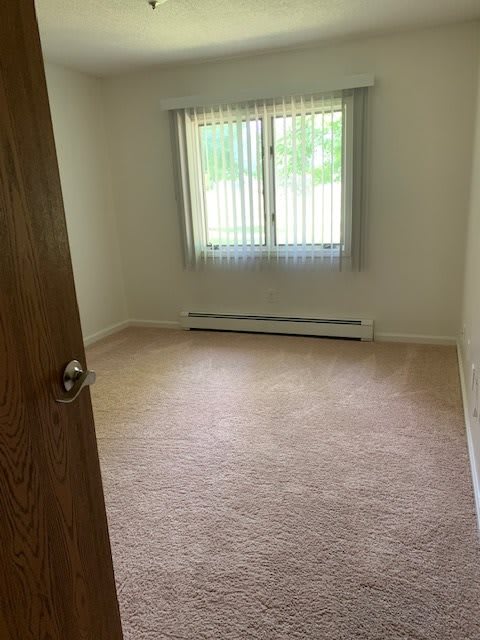 An empty room with carpet flooring and a window covered by blinds.