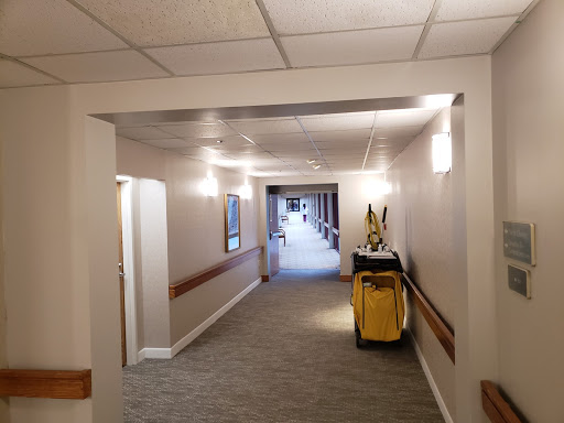 A well-lit hallway featuring a cleaning cart, characterized by a clean and inviting carpet.