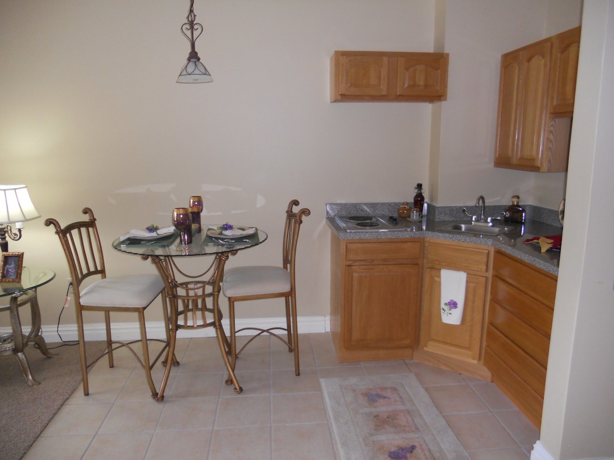 A cozy kitchen and dining area with wooden cabinets and a small round table set.