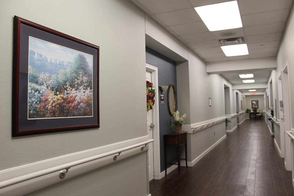 A well-lit hallway with artwork on the wall and doors along the corridor.