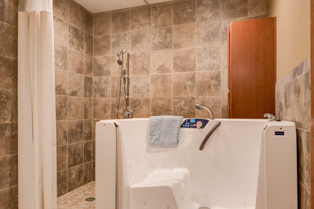 A modern bathroom featuring a walk-in tub with tiled walls and an accessible shower.