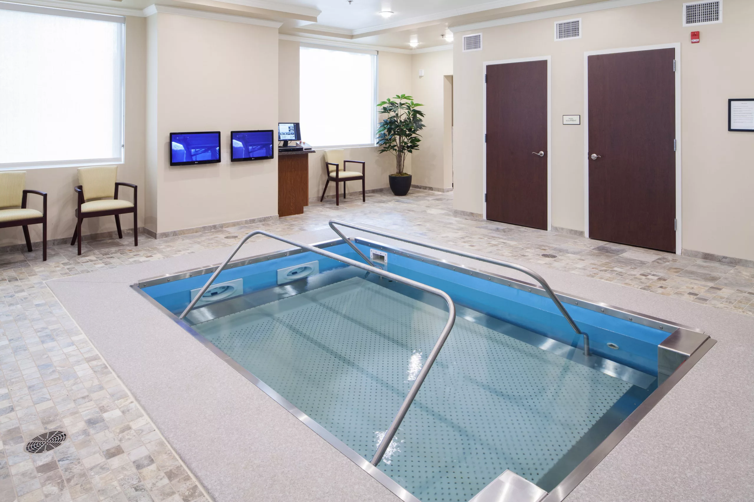 An indoor therapy pool in a healthcare facility, equipped for physical rehabilitation exercises.