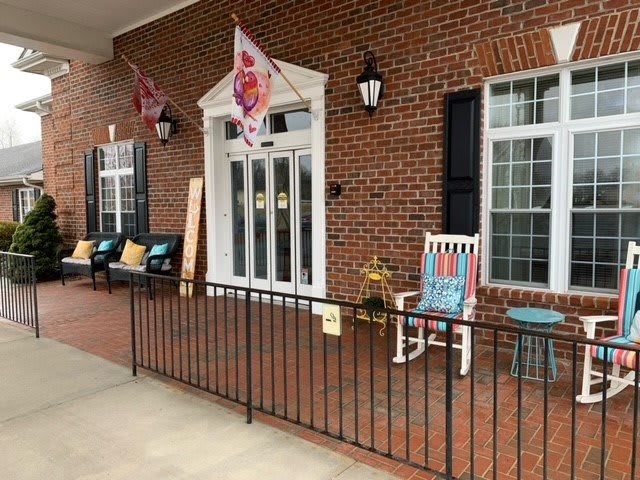 A cozy porch with a rocking chair and decorative flags on a brick building.