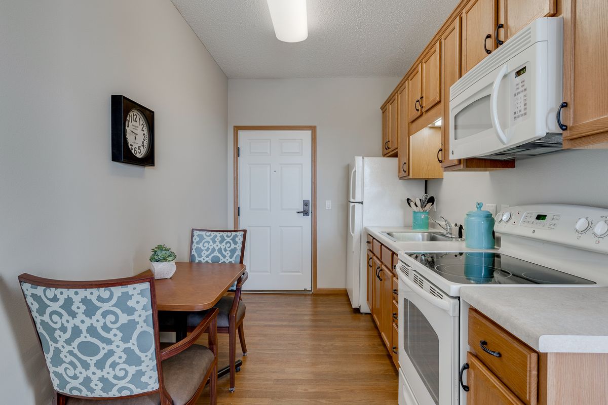 A modern kitchen with wood cabinets, a small dining table, and essential appliances.