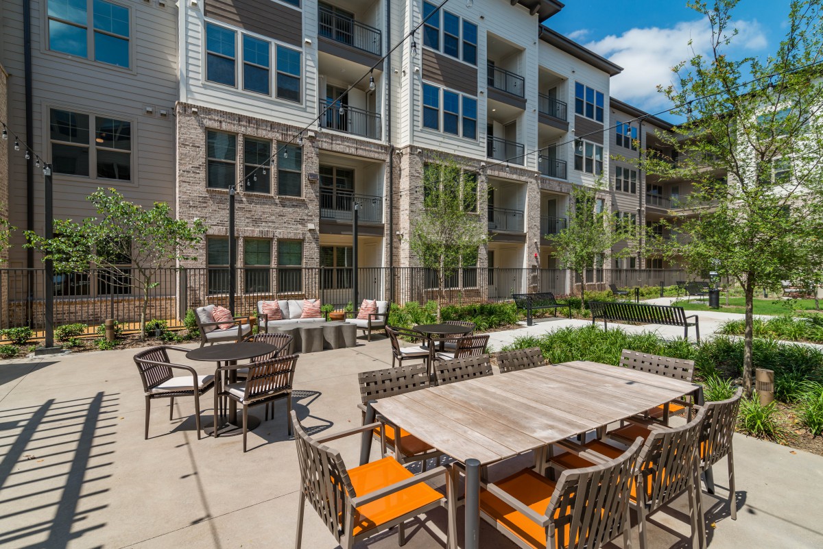 A modern apartment building with outdoor patio seating in a residential area.