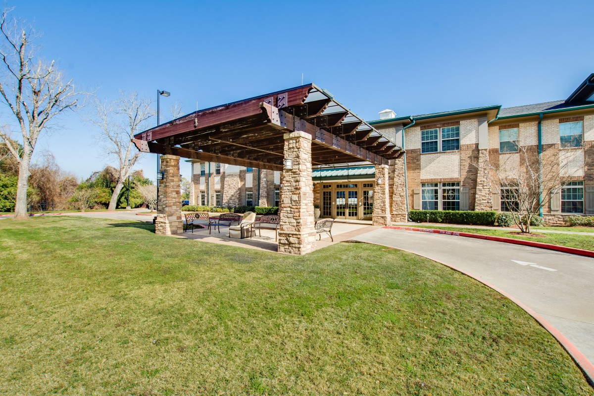 A modern building with a covered outdoor entrance and well-maintained lawn.