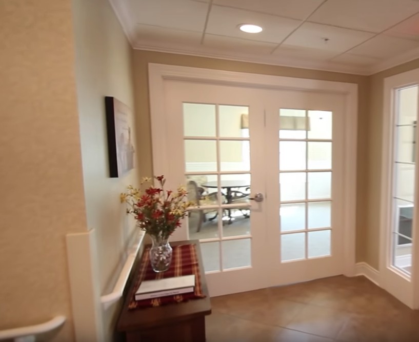 A hallway featuring double doors with a decorative table and vase of flowers.