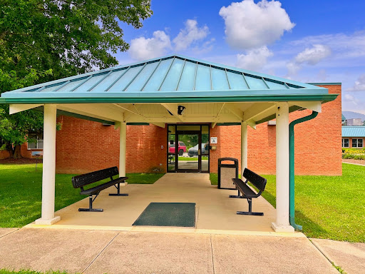 A welcoming entrance with a covered area, benches for seating, and lush green surroundings.