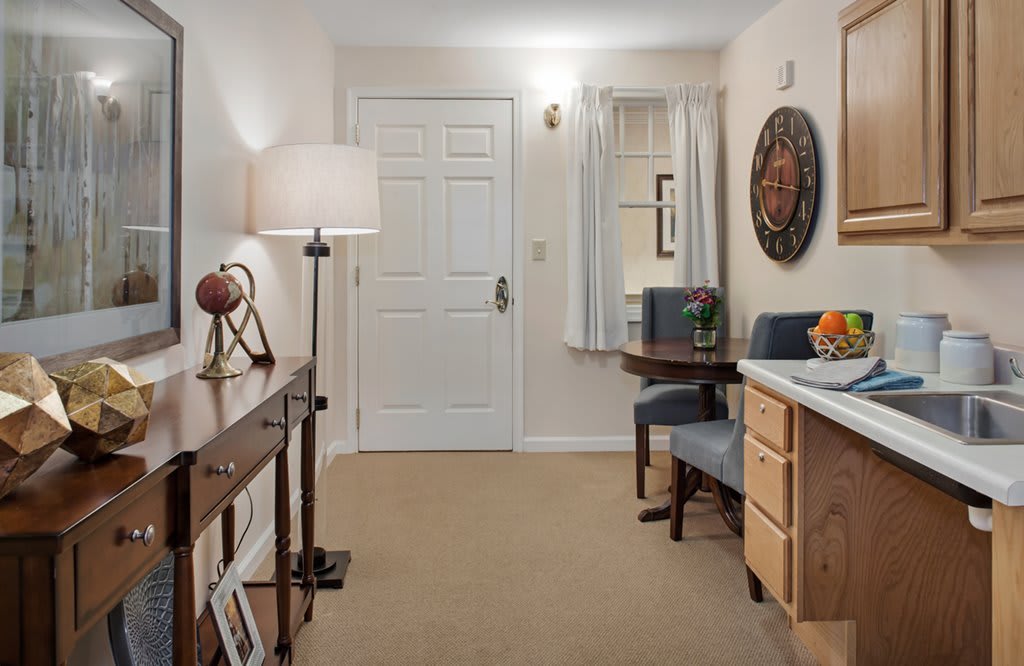 A cozy interior featuring a desk with two chairs, a decorative clock on the wall, and a standing lamp.