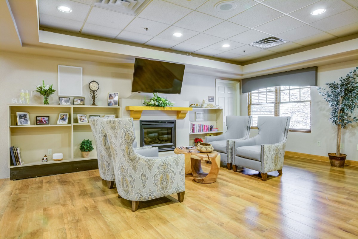 A cozy and elegantly designed living room featuring a fireplace, armchairs, and a mounted television.