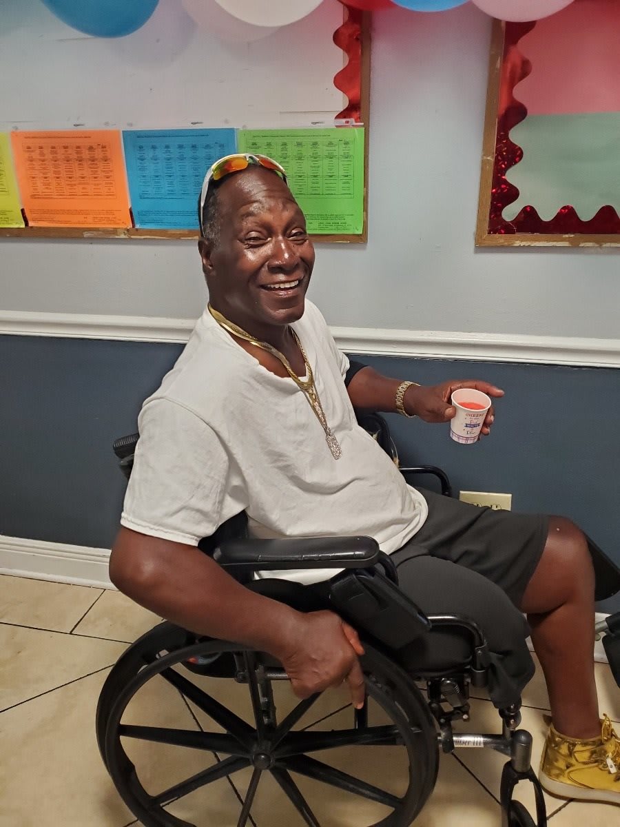A man in a wheelchair smiling indoors.