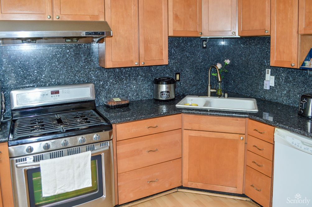 A modern kitchen with wooden cabinets, a stainless steel stove, and a deep sink.