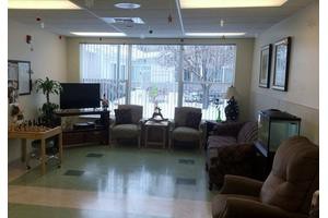 A cozy waiting area with several chairs, a television, and large windows letting in natural light.