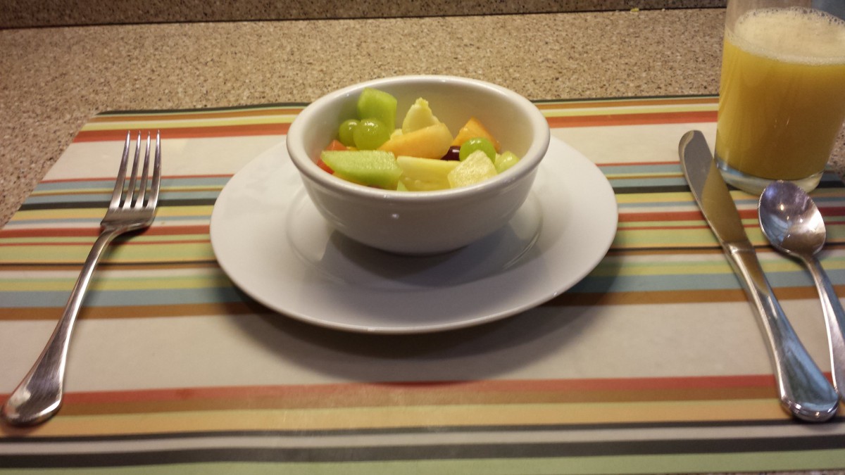 A bowl of mixed fruit on a striped placemat.