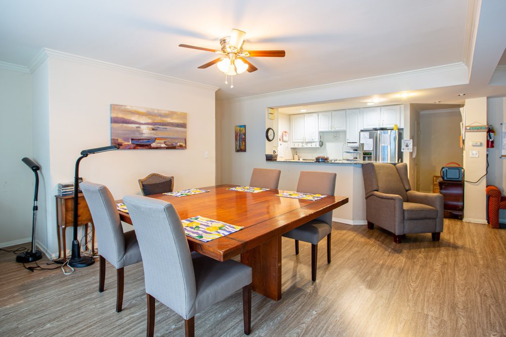 A cozy dining room with a wooden table, cushioned chairs, and an open view into the kitchen.