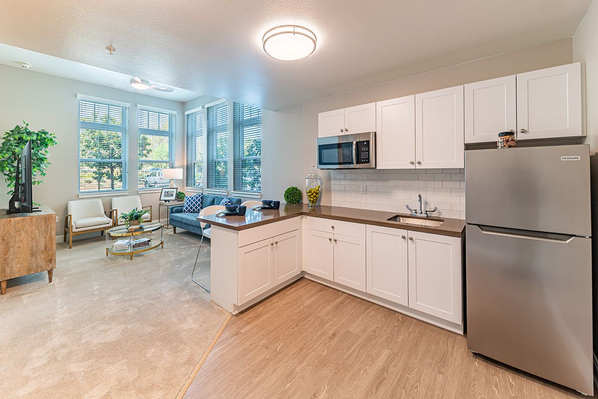 A modern open-concept kitchen and living room with white cabinetry and ample natural light.