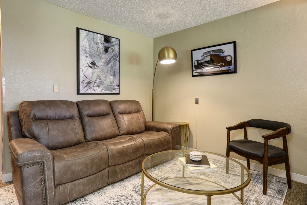 A cozy living room with a brown sofa, stylish lamp, and modern decor.