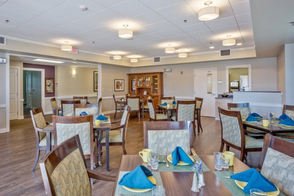 A neatly arranged dining room with tables set for service, featuring elegant decor and soft lighting.