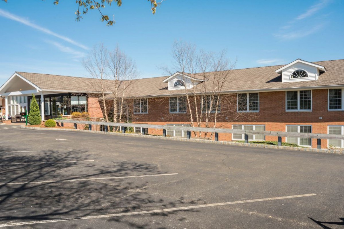 A brick school building with a parking lot in front.