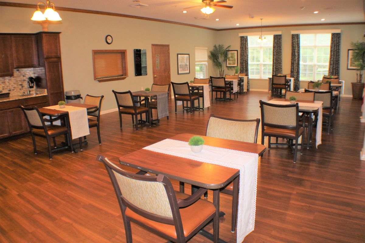 A spacious dining room with multiple tables and chairs, designed for community gatherings.
