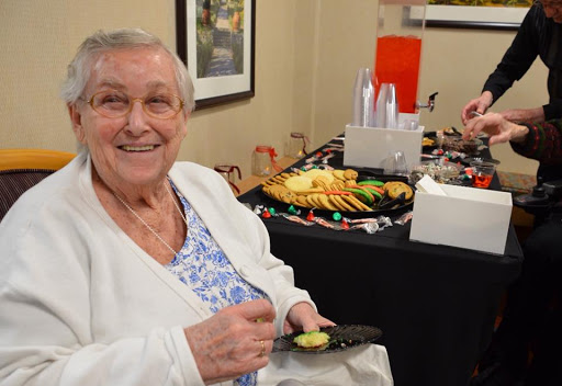 An elderly woman enjoying a snack at a social event.