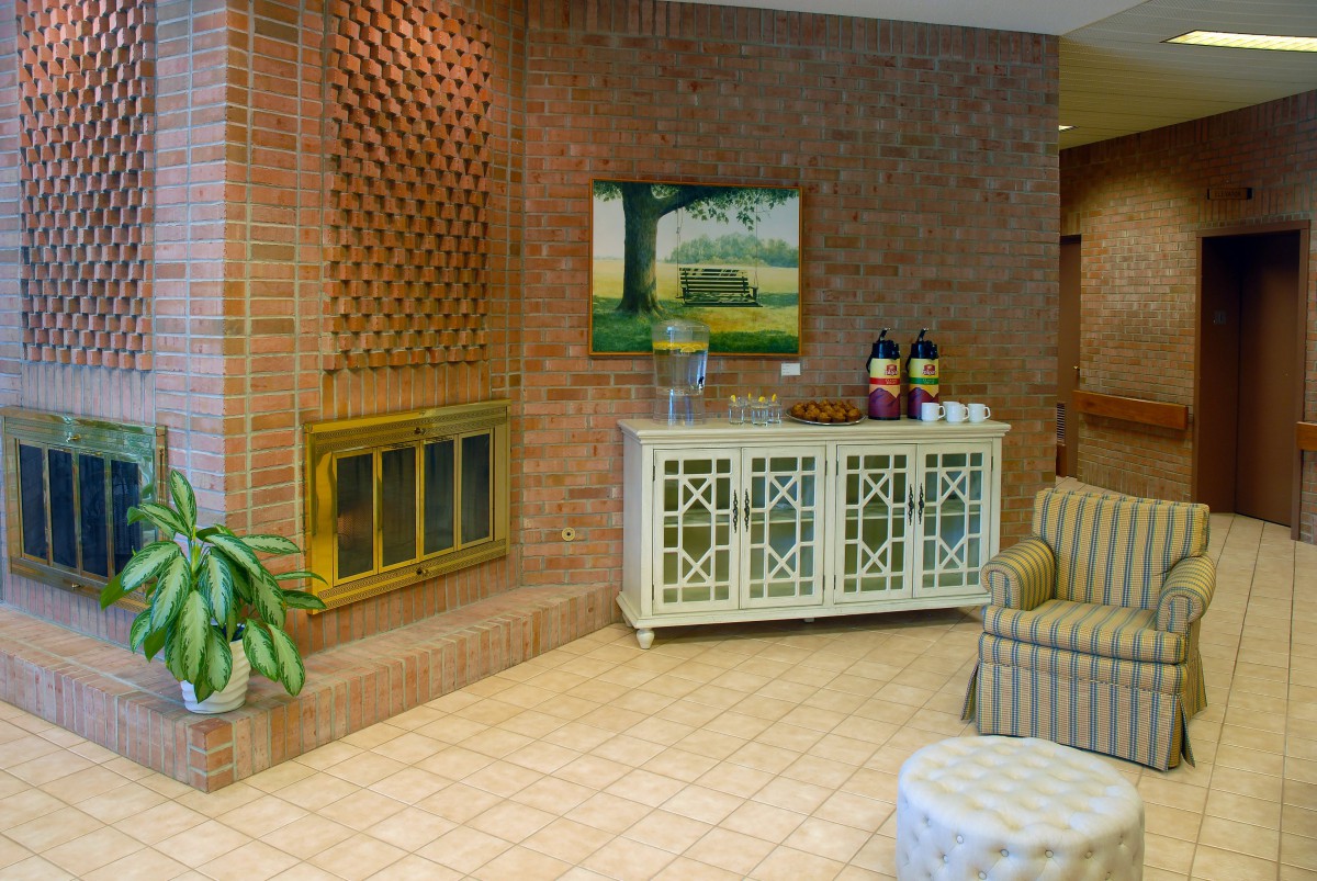 A cozy lobby with a brick fireplace, seating area, and a coffee station.