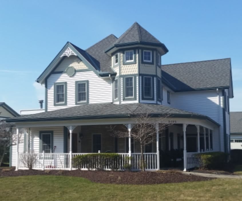 A Victorian-style house with a prominent round tower and wrap-around porch.