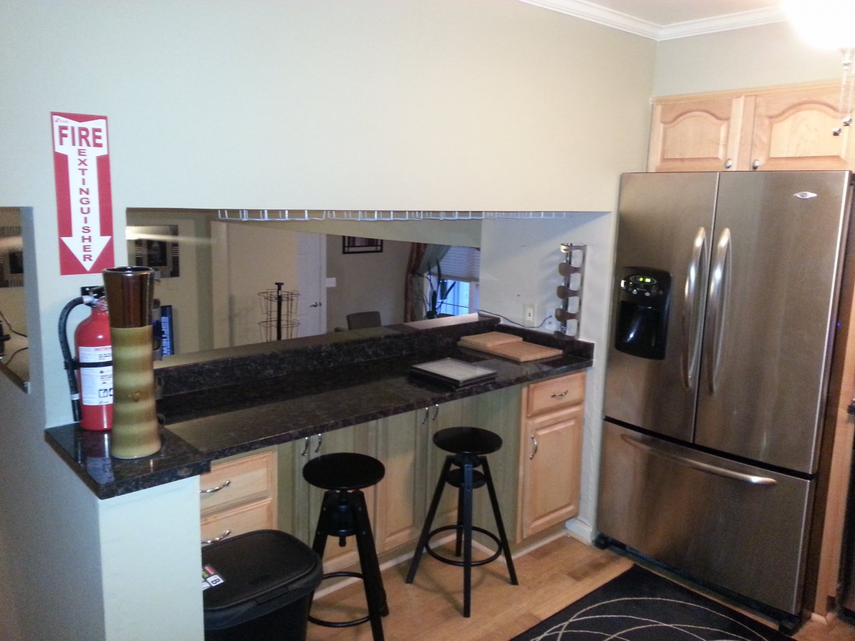 A modern kitchen with wooden cabinets, a stainless steel refrigerator, and a mirrored backsplash accentuating the space.
