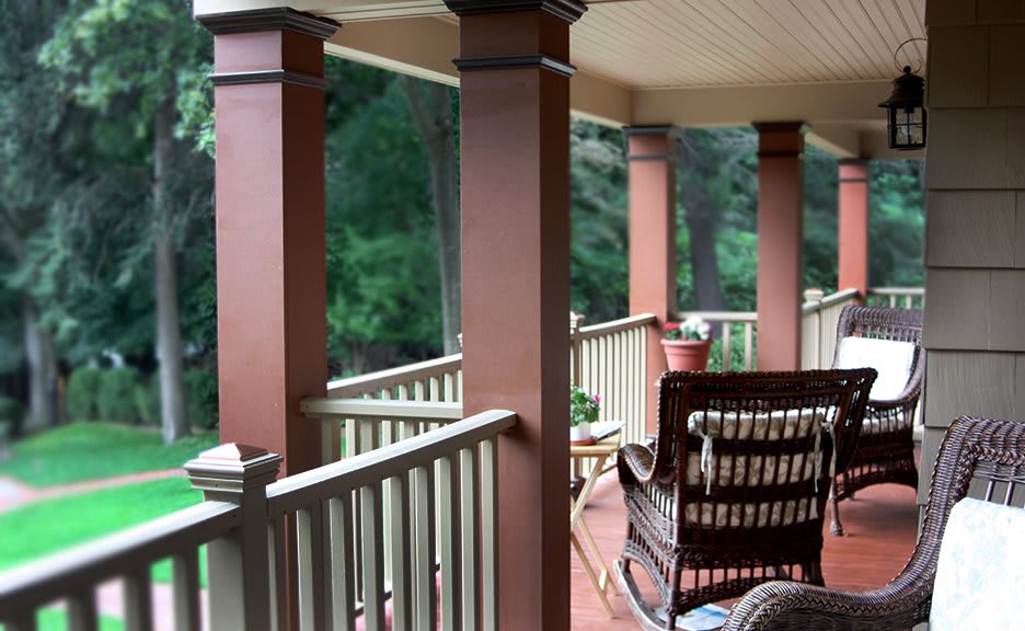 A cozy porch with chairs and columns overlooking a lush green landscape.