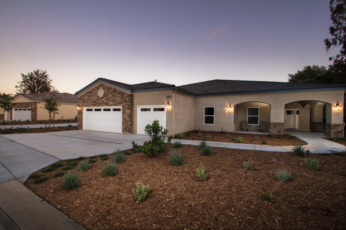 A modern single-story house with a two-car garage and landscaped front yard at dusk.