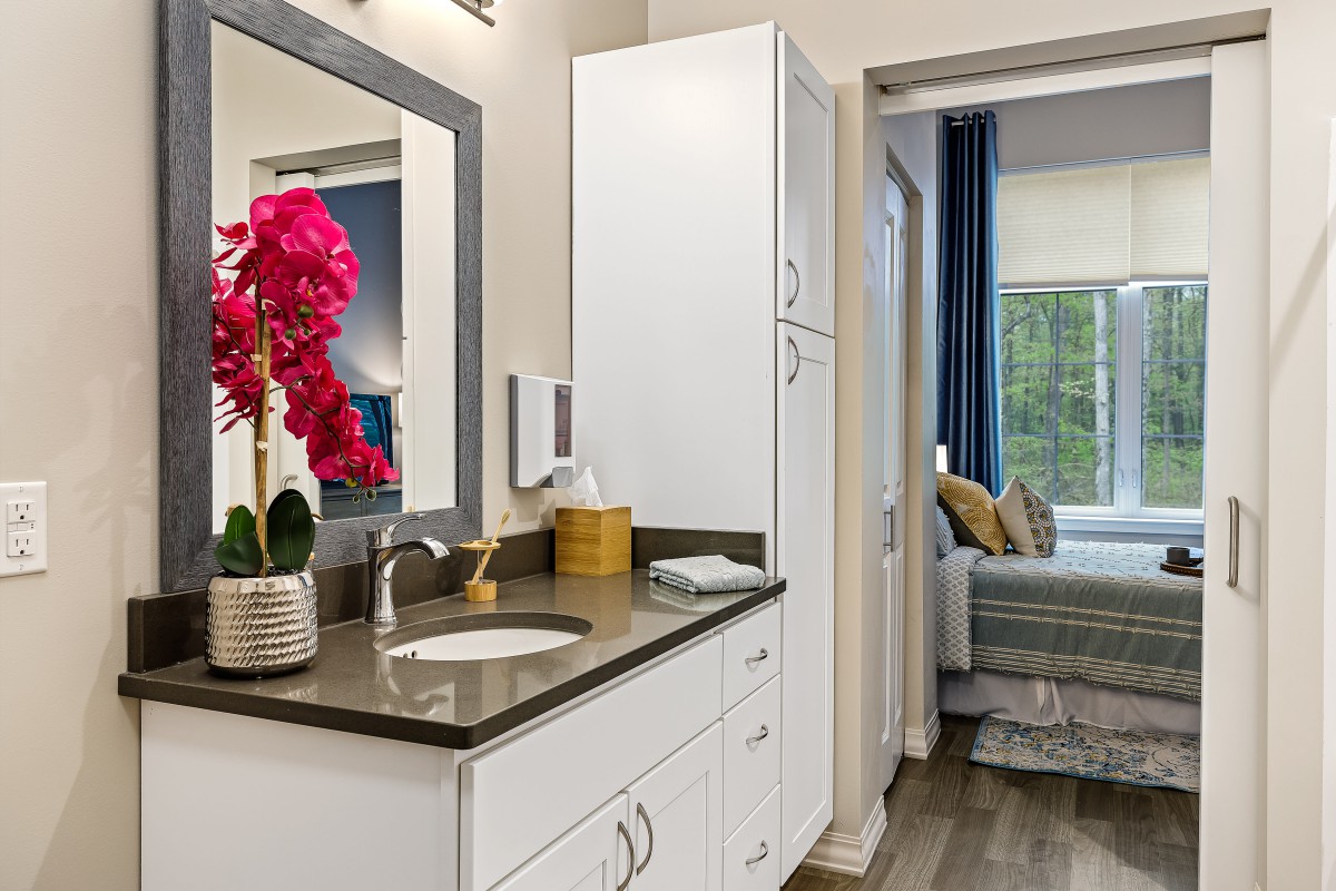 A modern bathroom with a sleek design featuring a sink, mirror, and vibrant orchid decor.