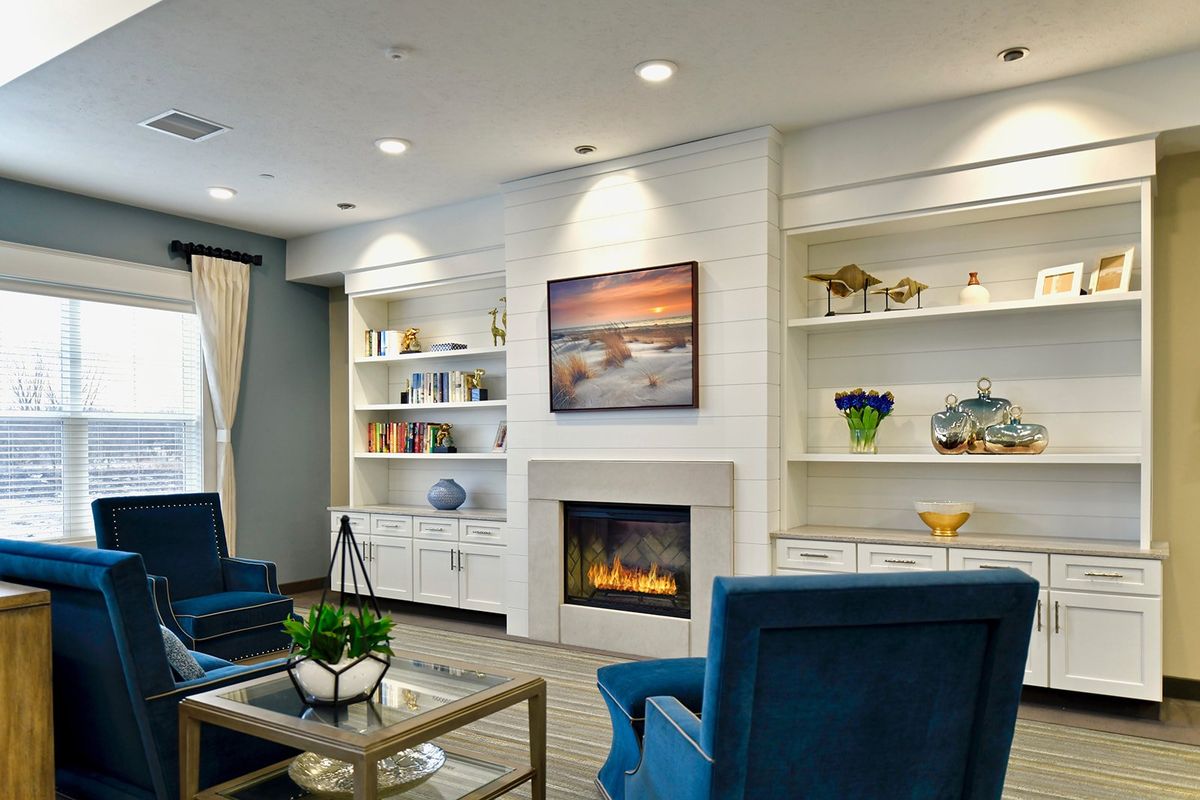 A modern living room with a fireplace, built-in shelves, and blue armchairs creating a cozy atmosphere.