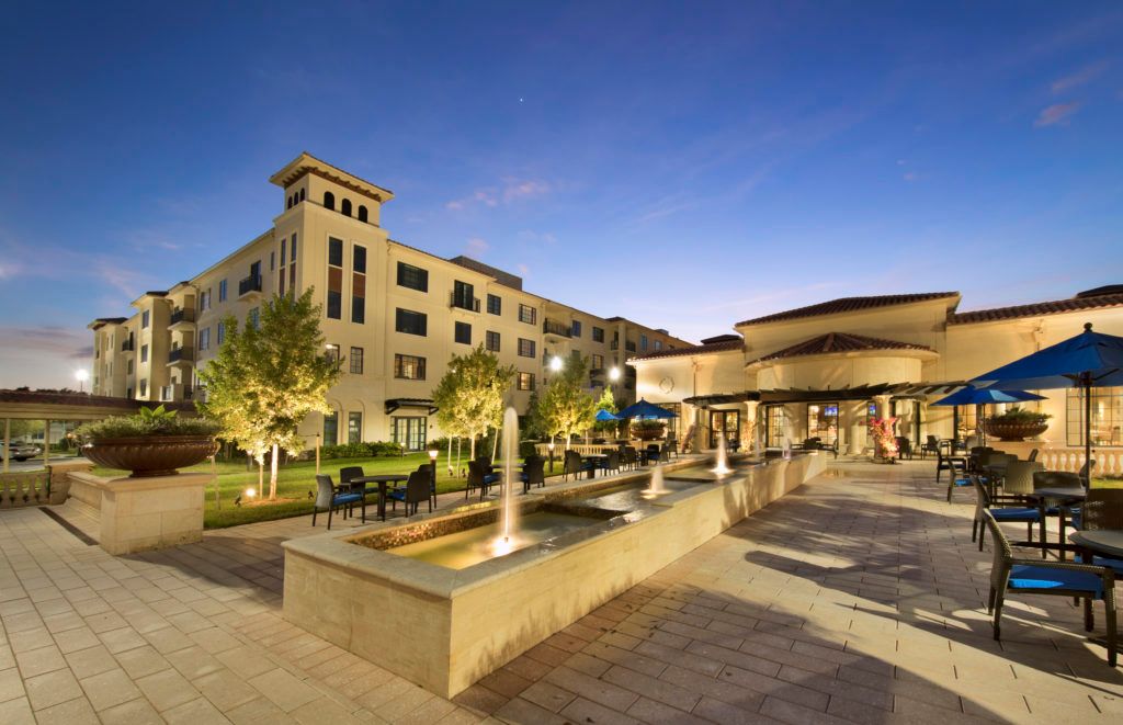 A scenic view of a hotel with fountains and landscaped gardens in the evening.