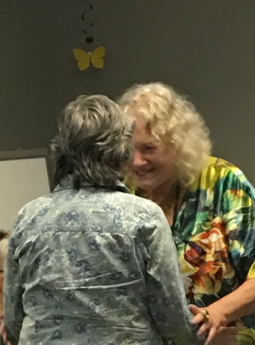 Two people smiling and conversing indoors.