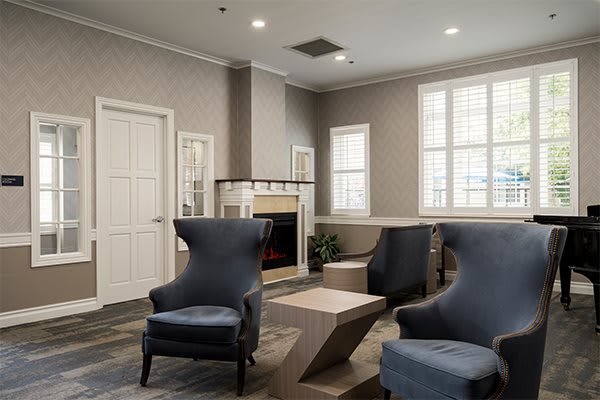 A modern living room with elegant armchairs and a fireplace, featuring neutral tones and contemporary design.