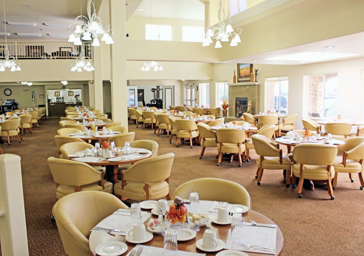 An elegant dining hall with neatly arranged tables and chairs, featuring warm lighting.