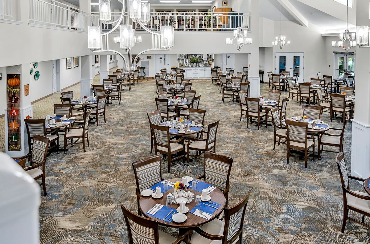 Spacious dining area with neatly arranged tables and elegant chandeliers.