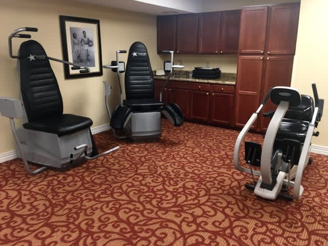 A small gym setup with various exercise machines on a patterned carpet.