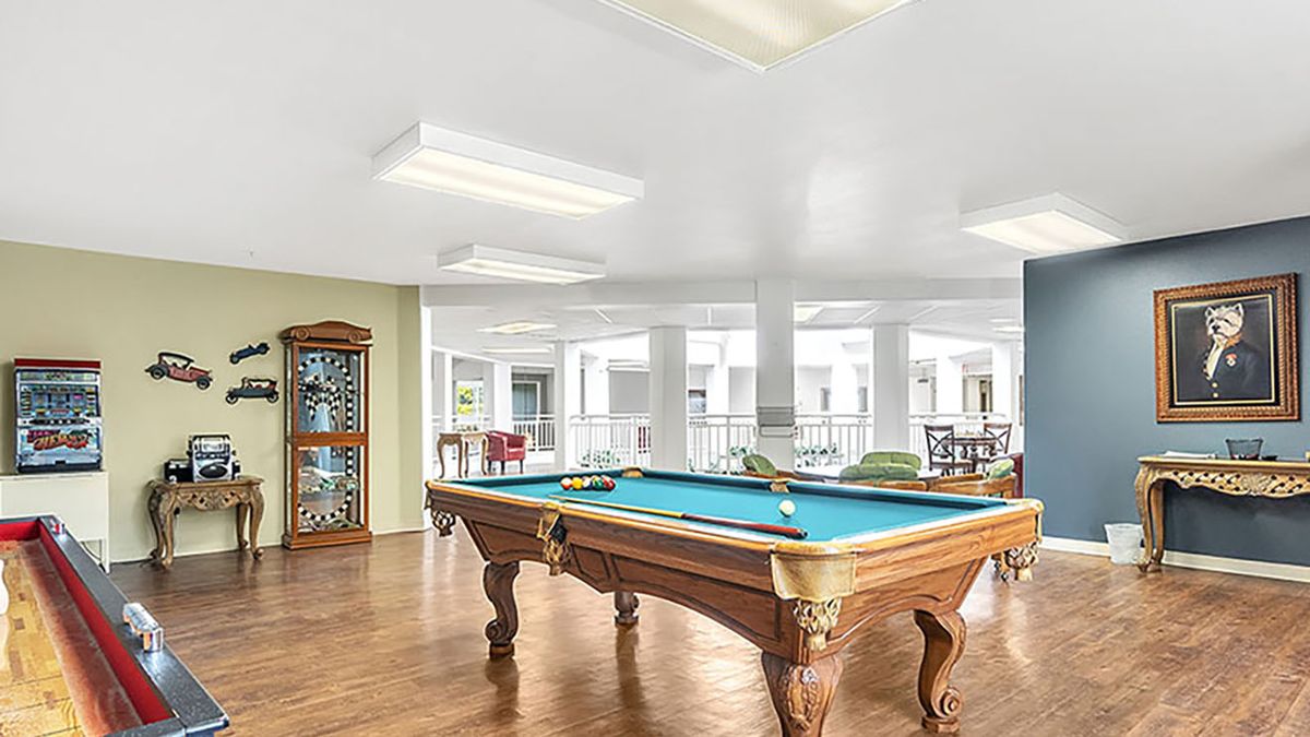 A well-lit game room featuring a pool table and wooden flooring.