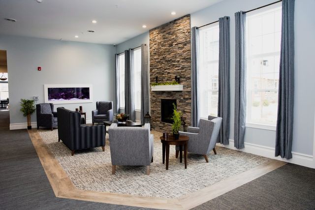 Modern living room with stone fireplace and gray furniture.