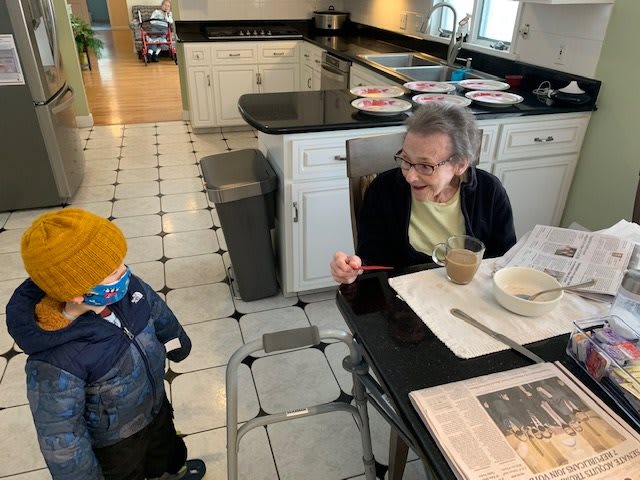 A child and an elderly woman share a moment in the kitchen.
