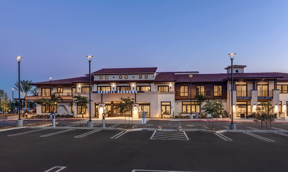 A modern building with a parking lot in the evening.