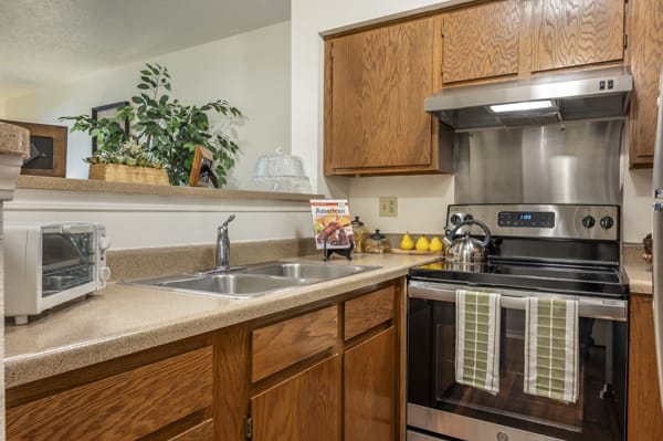 A well-organized kitchen with wooden cabinets, an oven, and a sink.