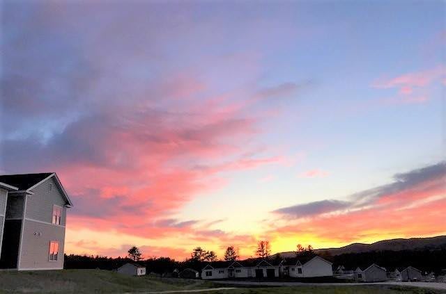 A stunning sunset with vibrant colors spreading across the sky over a quiet landscape.