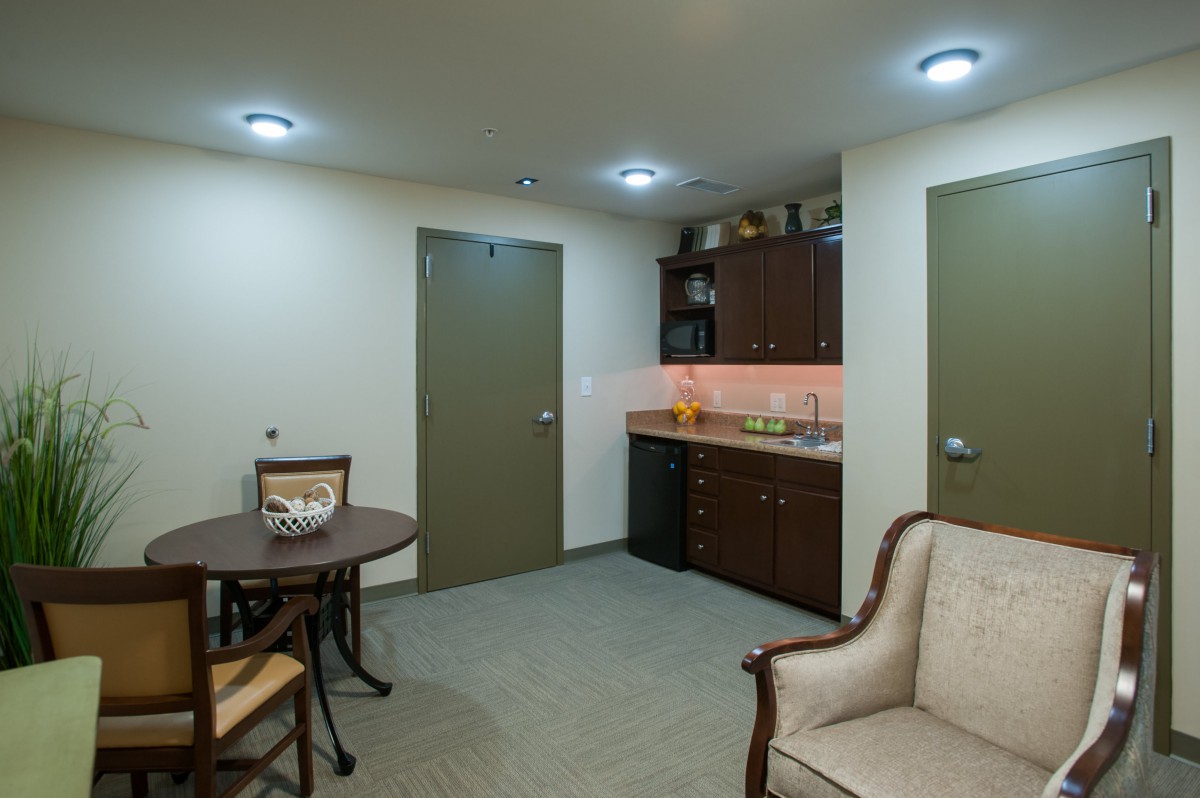 A cozy living area featuring a small kitchenette, a round table with chairs, and a soft armchair.